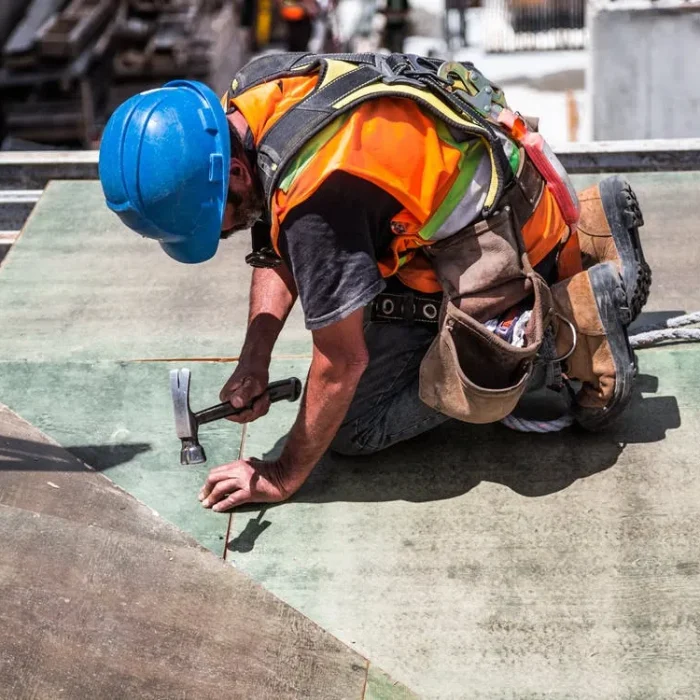 carpenter affixing plywood to building under construction